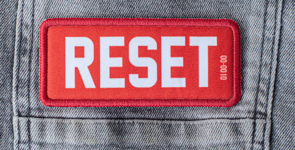 RESET Founding Patch on denim jacket — 
NFC embedded, numbered, non-fungible. One of 1,000.